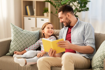 family, leisure and people concept - happy father and daughter reading book at home