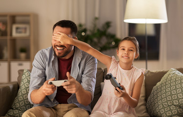 family, gaming and entertainment concept - happy father and little daughter with gamepads playing...