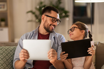 family, fatherhood and technology concept - happy father and daughter in glasses with tablet pc...