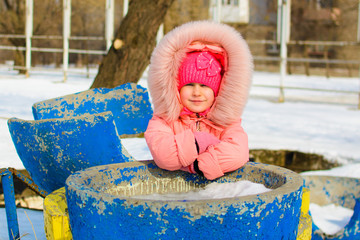 Little boy in jacket and knitted hat catching snowflakes in winter park on Christmas. Child playing...