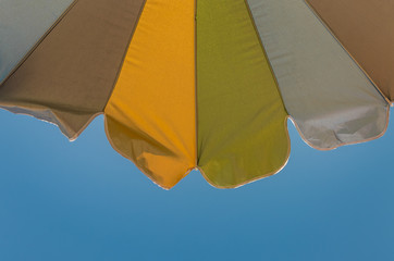 Multicolored sun umbrella against a blue sky on the sea beach