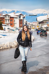 Fototapeta premium beautiful girl walking by street in bulgarian ski resort Bansko, Bulgaria ,winter