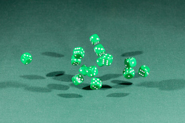 Fifteen green dices falling on a green table