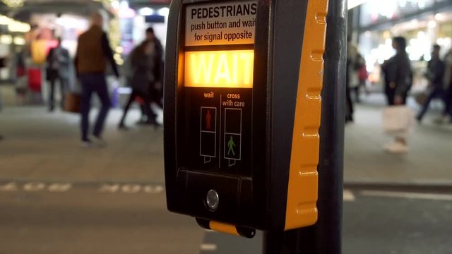 Pedestrian pushes button and waits for the green sign at a crossing