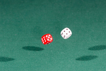 Two red and white dices falling on a green table