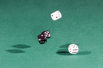 Four white and black dices falling on a green table