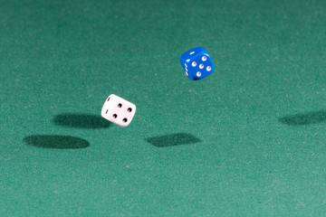 Two white and blue dices falling on a green table