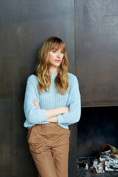 Junge Frau steht vor rostiger Metallwand mit offenem Kamin