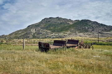 Obraz premium The old Soviet auto and agricultural machinery abandoned in the steppe not far from Sartymbet village, stone mountains 