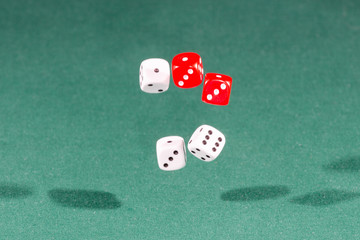Four red and white dices falling on a green table