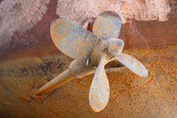 Rusted shaft of a ship and a screw come out of the hull of the ship in dry dock