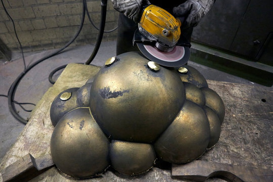 Arbeiter schleift Metall Skulptur mit Trennschleifer Flex