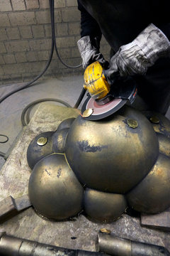 Arbeiter schleift Metall Skulptur mit Trennschleifer Flex