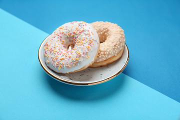 Plate with sweet tasty donuts on color background