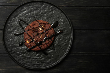 Plate with tasty chocolate cookie on dark wooden table