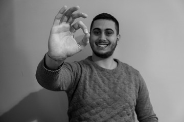 Portrait of a young boy smiling while doing 'ok' with his hand.