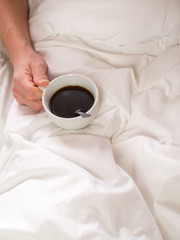 Katerfrühstück - Mann mit einer Tasse Kaffee in der Hand im Bett