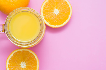 Colorful composition with mason jar glass full of fresh orange juice with straw, fruit, isolated on pink background. Close up, copy space, top view.