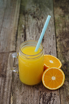 Fresh orange juice in the mason jar on wood table, rustic wooden table. Vertical image.