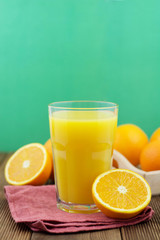 Colorful composition with mason jar glass full of fresh orange juice with straw, fruit, isolated on green background. Close up, copy space, top view.