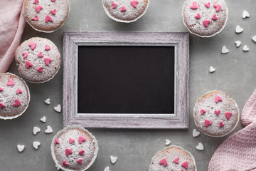 Blackboard framed with sugar-sprinkled muffins with pink and white fondant icing hearts