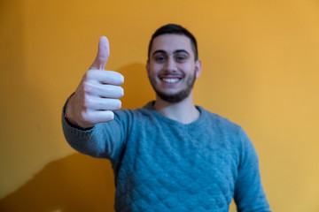 Portrait of a smiling young boy while he thumbs up with his hand.