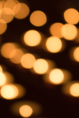 Blurred golden lights background. Defocused yellow and orange lights. GLowing illuminated texture. Glitter effect concept. Blurry warm festive wallpaper. Christmas design. 