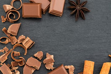 Broken chocolate pieces and chocolate shavings on a dark background. Top view with copyspace for your text