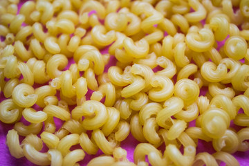 A bunch of yellow pasta on a pink background macro shot