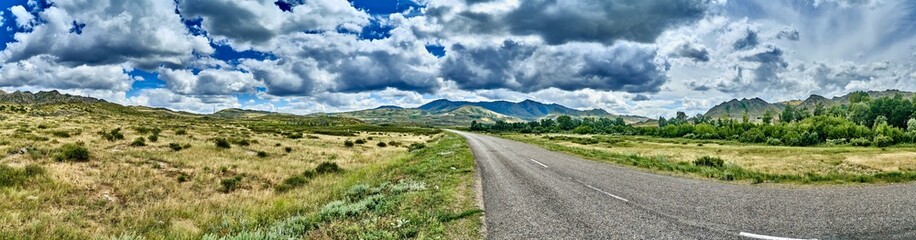 Fototapeta premium Beautiful landscape of steppe and stone mountains along the road from the city of Ust-Kamenogorsk to the Sibiny lakes (RU: Sibinskiye Ozora: Sadyrkol, Tortkara, Shalkar, Korzhynkol), East Kazakhstan