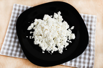 Cottage cheese on black plate top view. Healthy homemade food.