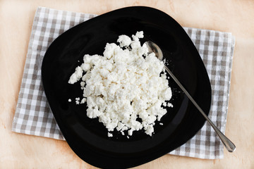 Cottage cheese on black plate top view. Healthy homemade food.