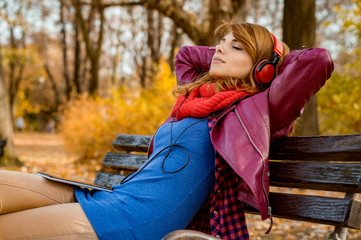 Beautiful young woman listening to music while resting in park