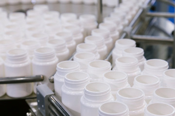 white plastic bottle on the production line of the conveyor at filling machine in the medical factory. selective focus.