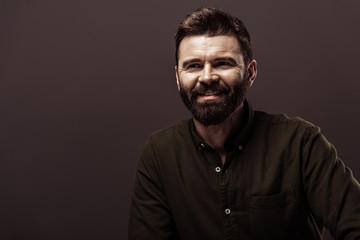 Obraz premium handsome bearded man in brown shirt smiling isolated on brown