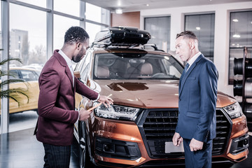 Professional car consultant wearing dark red jacket assisting client