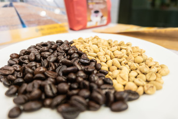 Dry raw coffee bean and roasted coffee bean on white dish