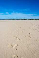 footprints in the sand with lighthouse in distance