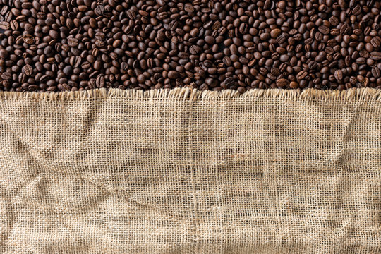 coffee beans in burlap sack on old wooden background. top view
