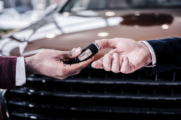 Sales manager passing keys from new brown hatchback car to new owner