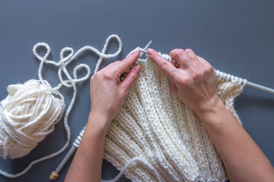 Woman's hands knitting white wool yarn pattern. Closeup horizontal photo. Freelance creative handicraft concept, hobby and lifestyle