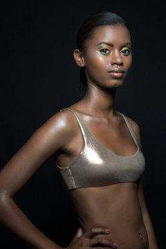 Beautiful, young, black woman wearing a metallic bikini top, portrait.