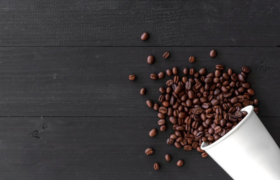 white paper cup and coffee beans on old wooden background. top view