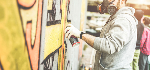 Graffiti artist painting with color spray on the wall for international competition - Urban, street art, millennials generation, mural concept - Focus on his hand