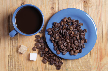 Top view of a blue cup of coffee and saucers with beans