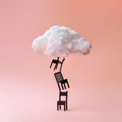 Stacked chairs with cloud against coral color background. Minimal success concept background.