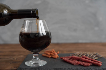  Red granat wine pouring from the bottle into wine glass, close-up 