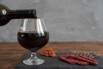  Red granat wine pouring from the bottle into wine glass, close-up 