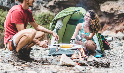 Naklejka na ściany i meble Trekkers couple cooking dinner in rock mountains