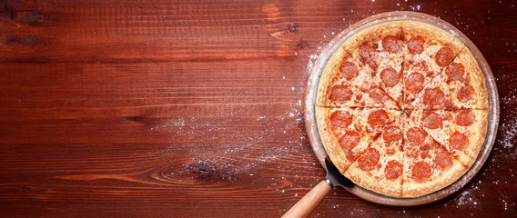 classic Italian pizza on a wooden tray, served in a small authentic Italian restaurant - obrazy, fototapety, plakaty